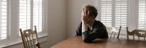 Man-Unhappy-Leaning-on-Wooden-Table