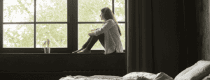 lonely looking student staring out of bedroom window